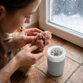Woman gently examining her dog's clean paw pads after winter walk with CradlePetss Paw Cleaner beside her - paw protection and care